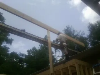 Carpenter setting a ridge beam over a new addition frame — Ice Dam Removal by Roofing Brothers in Briggs