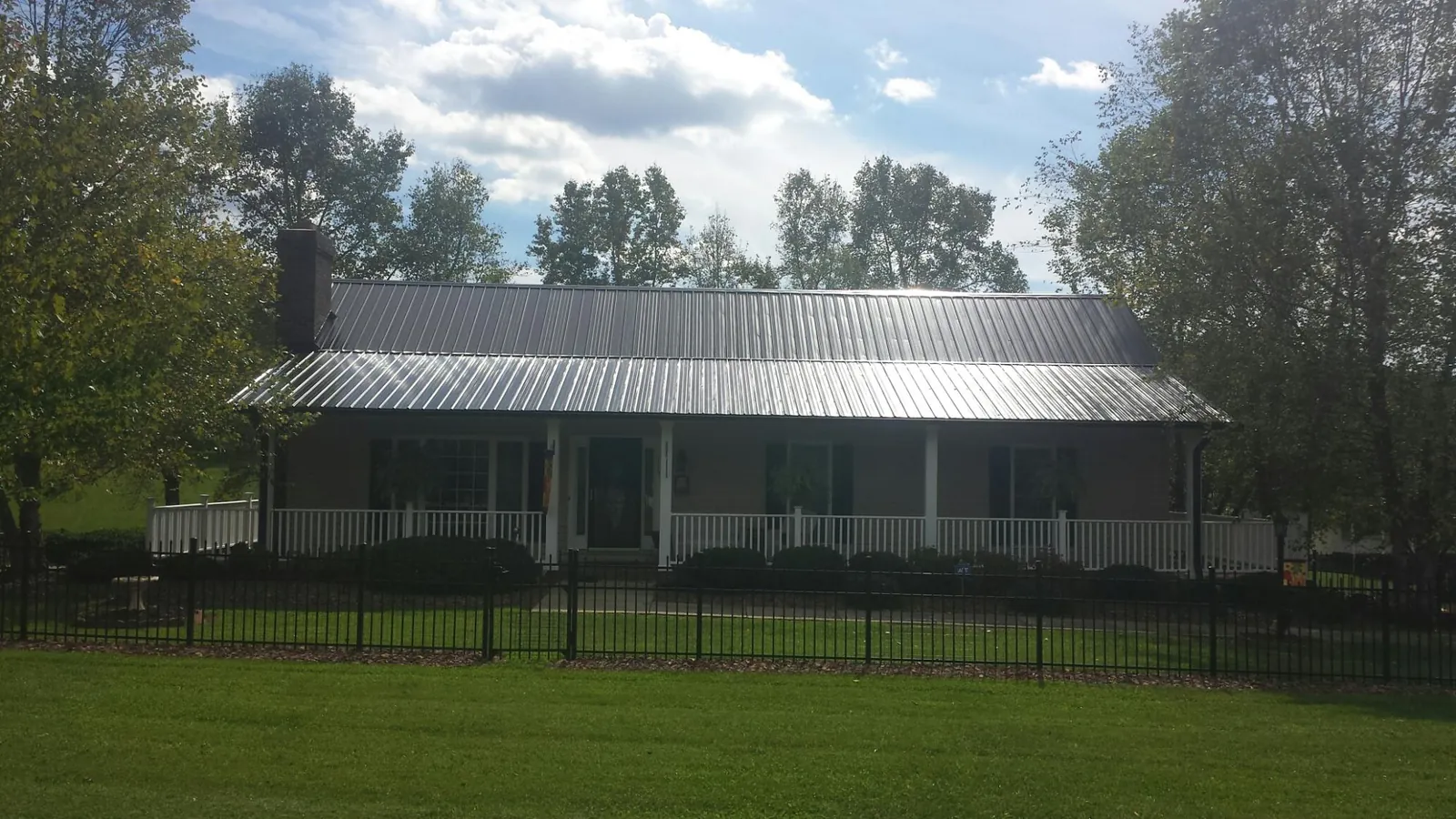 Gray metal roof on a brick ranch with a full width front porch — Gutter Guard Installation work by our crew in Briggs