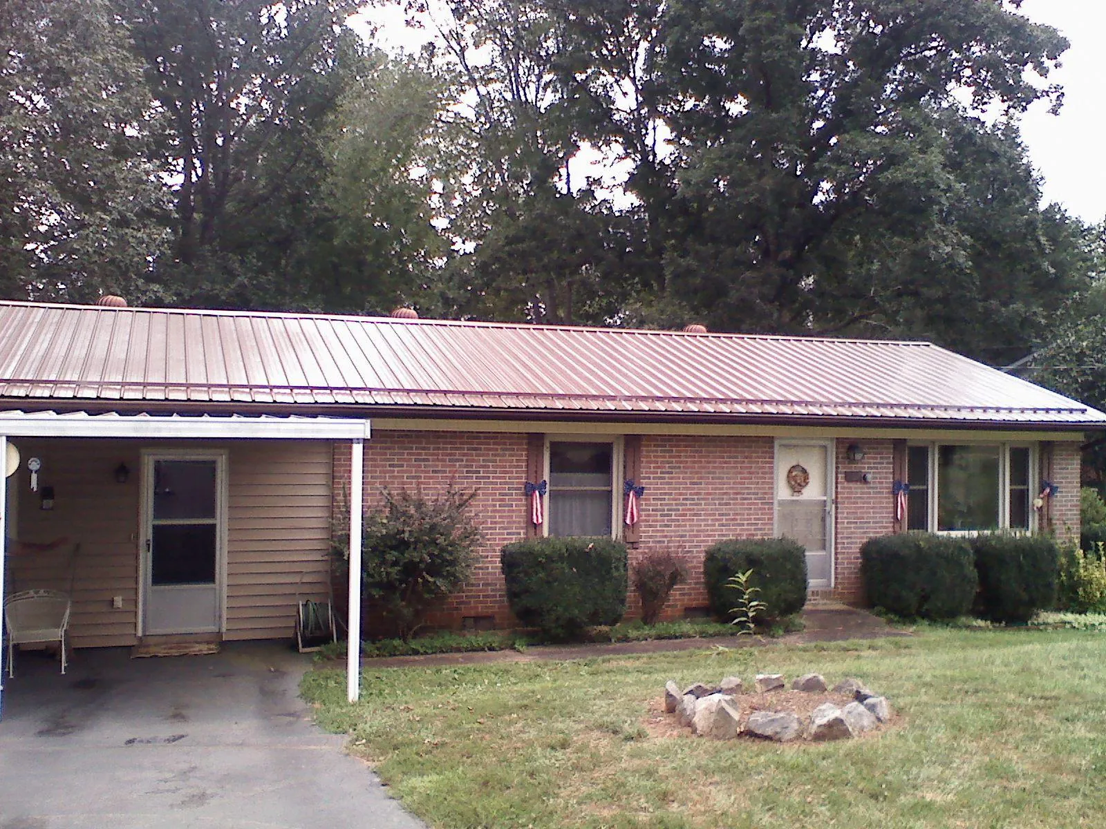 Bronze metal roof and carport on a brick ranch home — Roof Repair work by our crew in Briggs